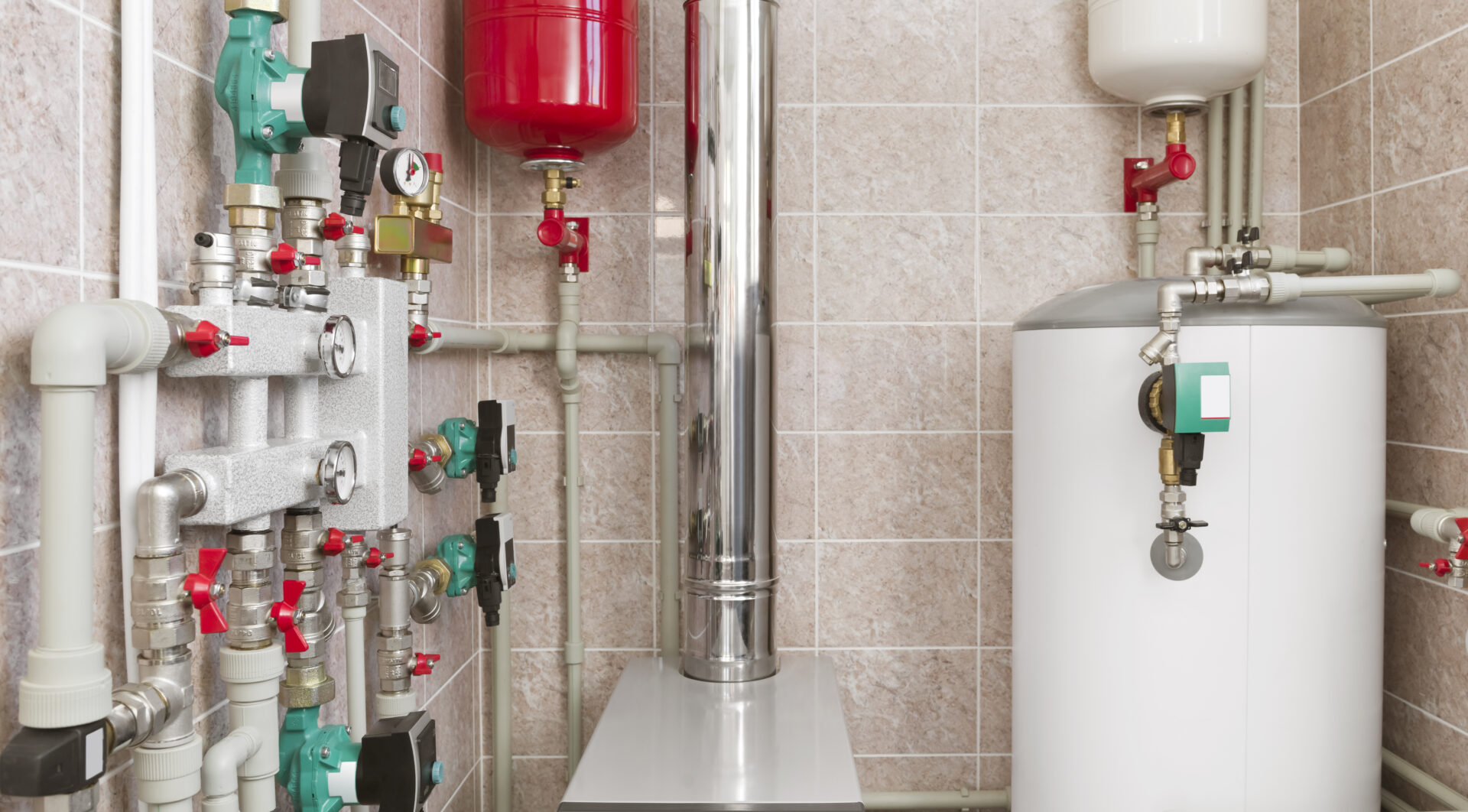 Boiler room with various pipes, valves, and pressure tanks against a tiled wall.